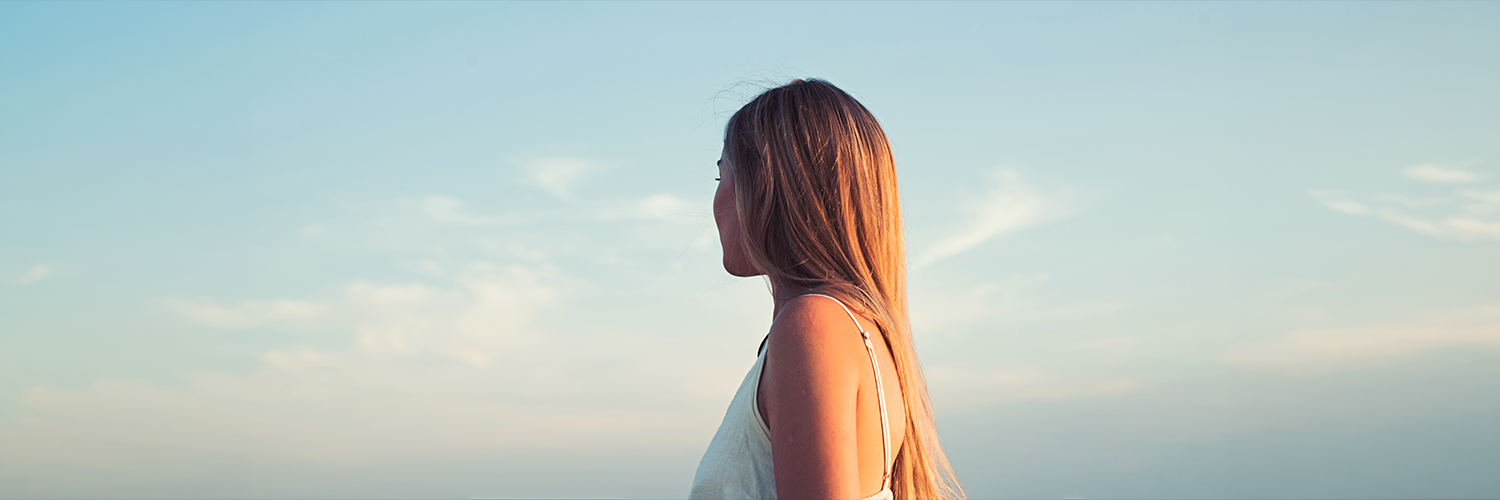遥か彼方を見つめる女性の後ろ姿